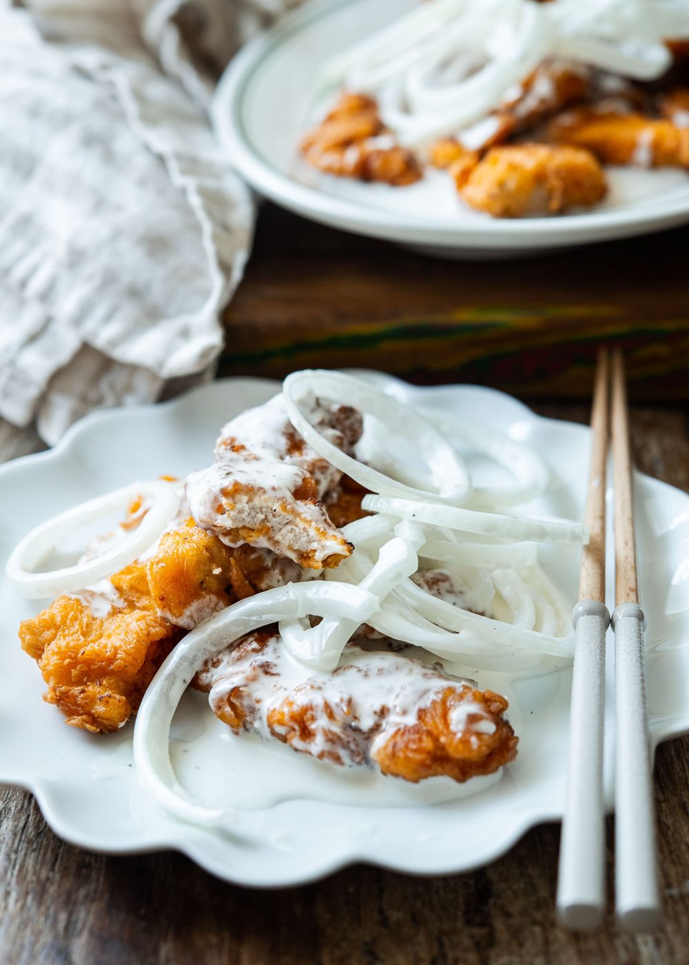 Pieces of fried chicken topped with snow onion sauce.