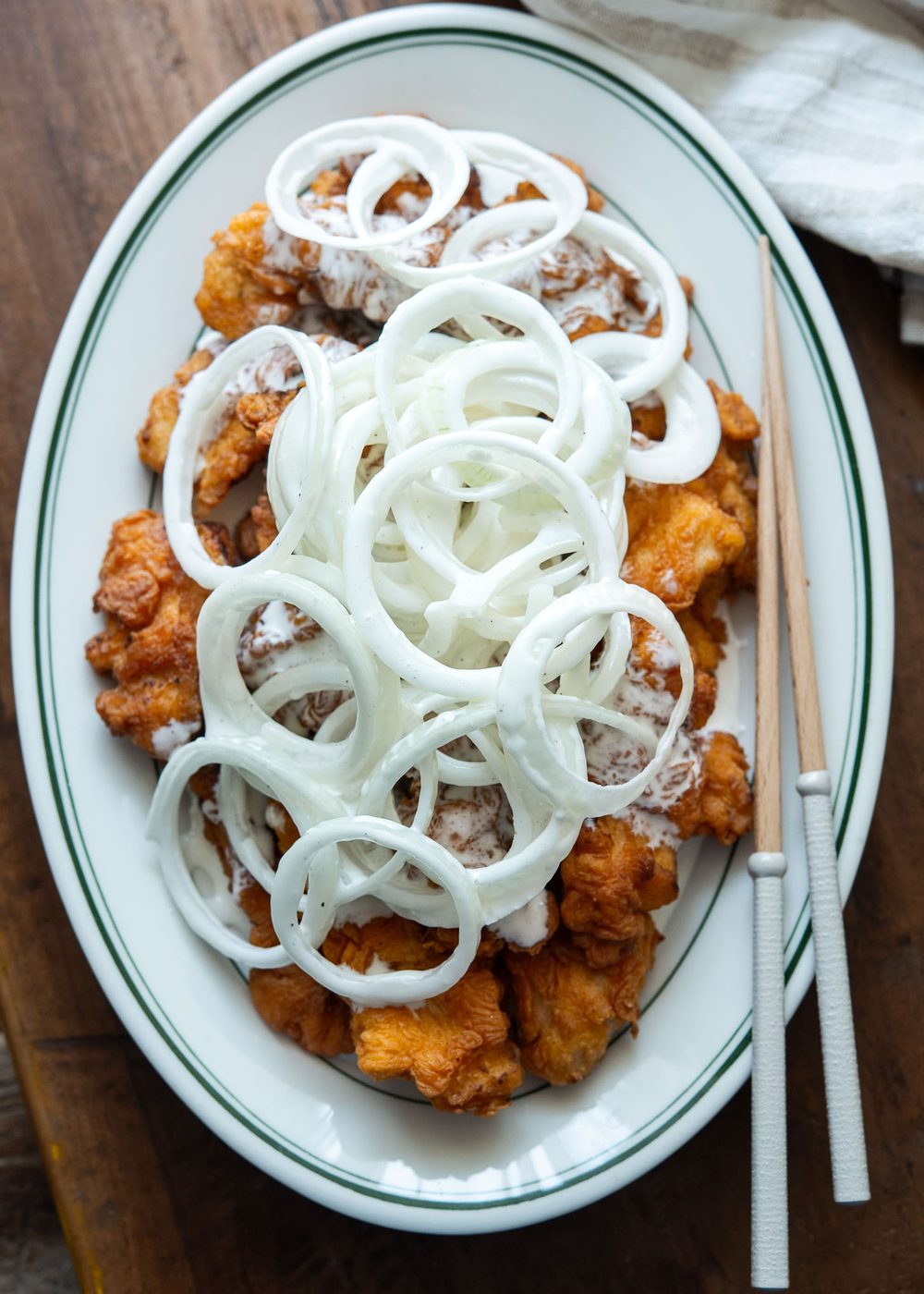 A plate of snow onion chicken with chopsticks.