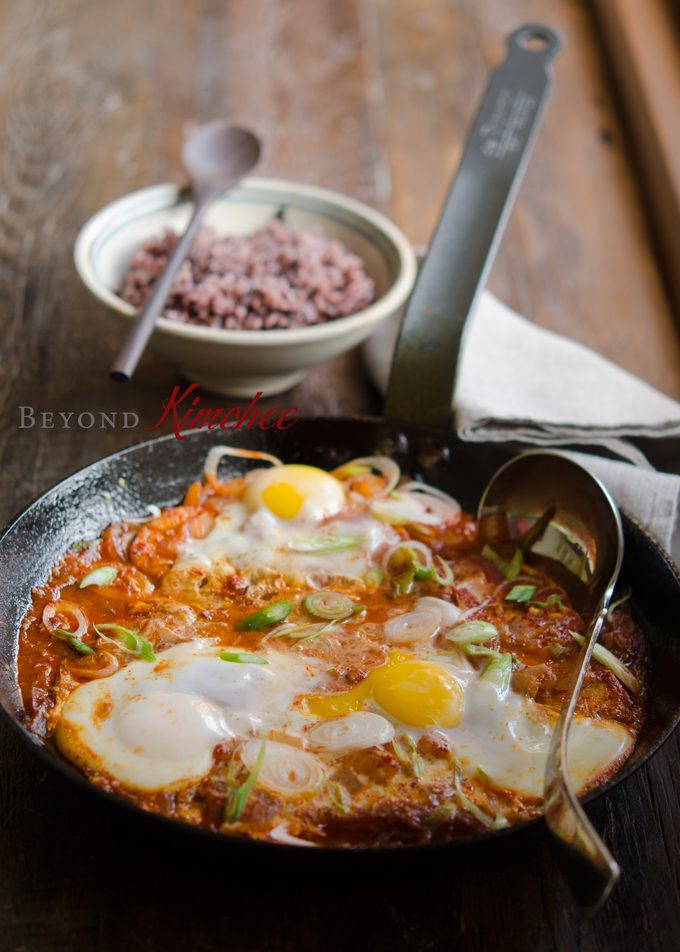 Tofu and eggs are cooked in a skillet with spicy sauce to serve with rice.