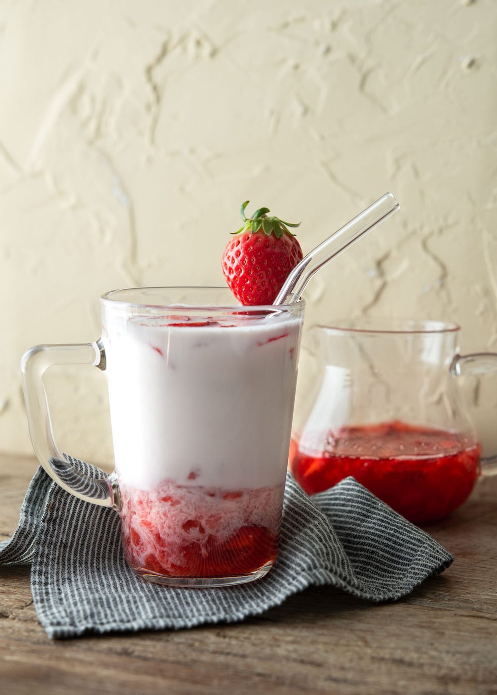 Korean strawberry milk has fresh strawberry syrup is in a glass cup garnished with a piece of strawberry.