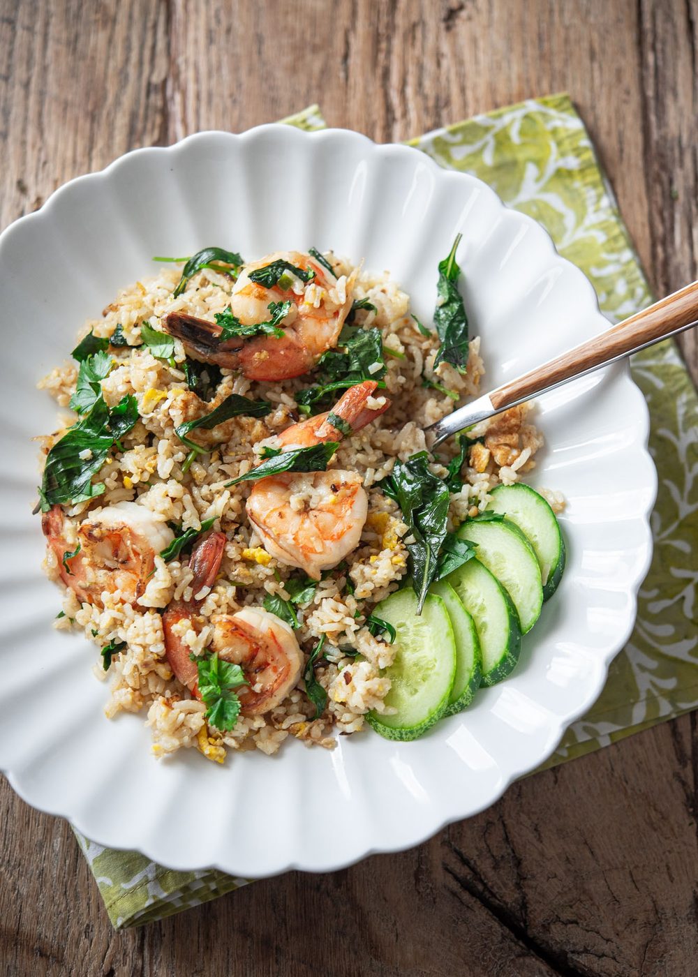 A serving of Thai basil fried rice with shrimp and cucumber slices on a plate