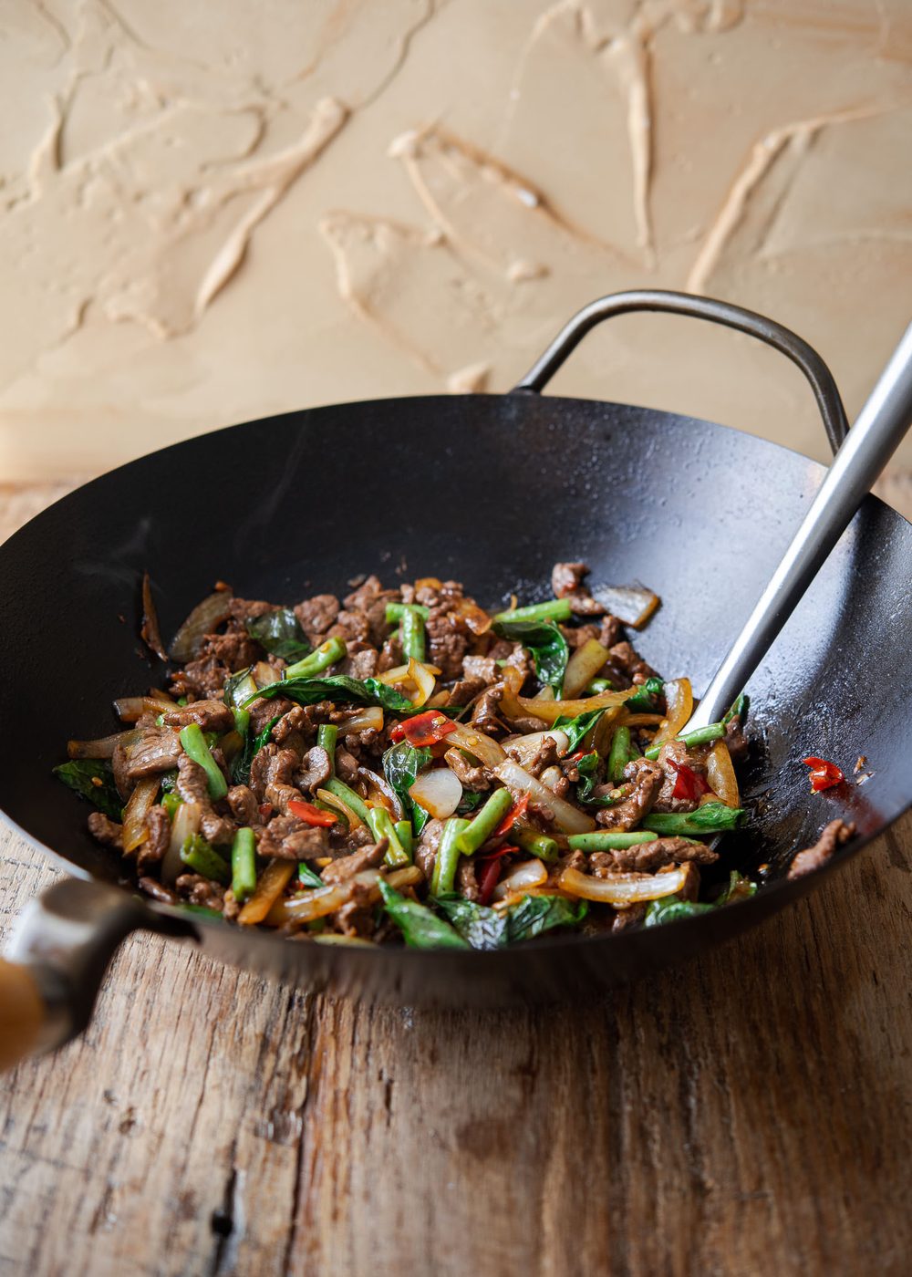 Thai basil beef stir-fried in a wok.