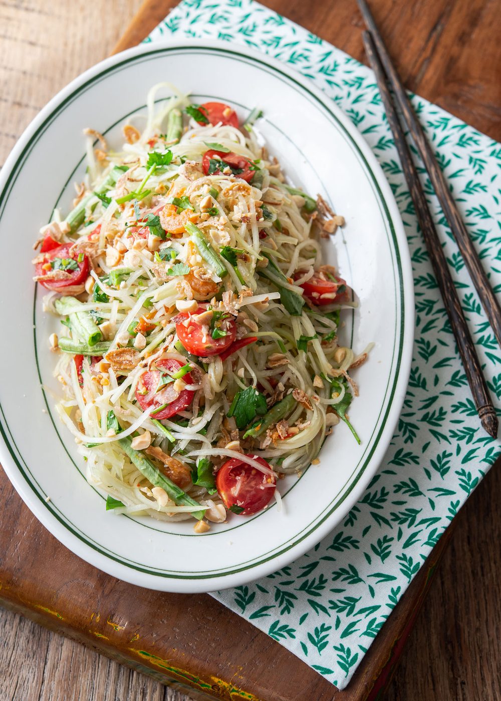 Thai papaya salad (som tam) served on a white oval plate.