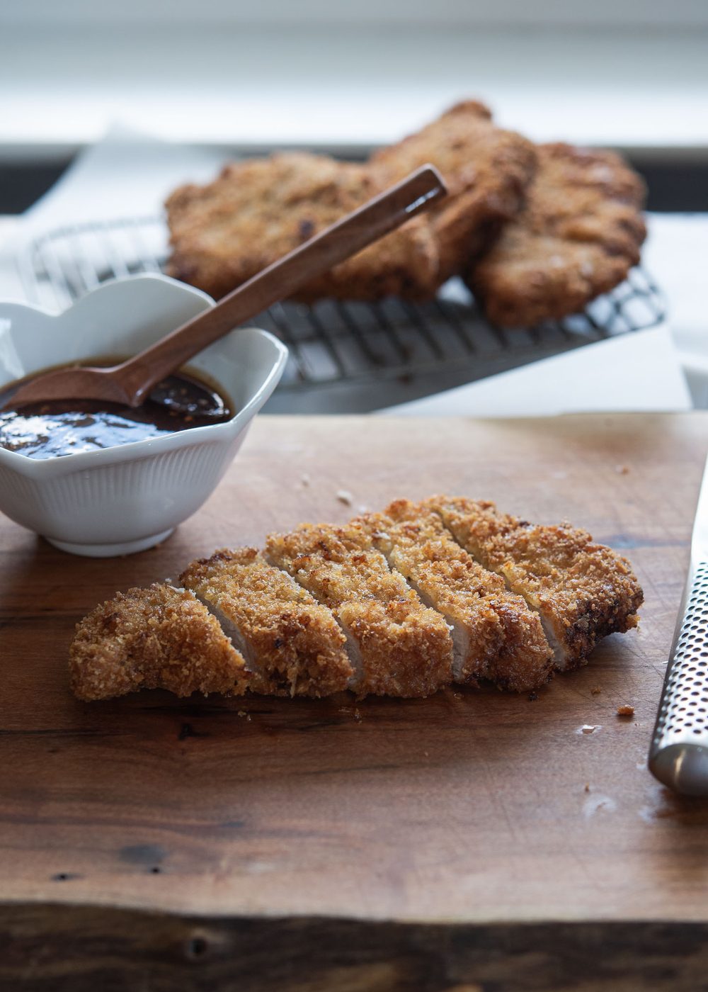 Crispy breaded pork cutlet on a board with dipping sauce