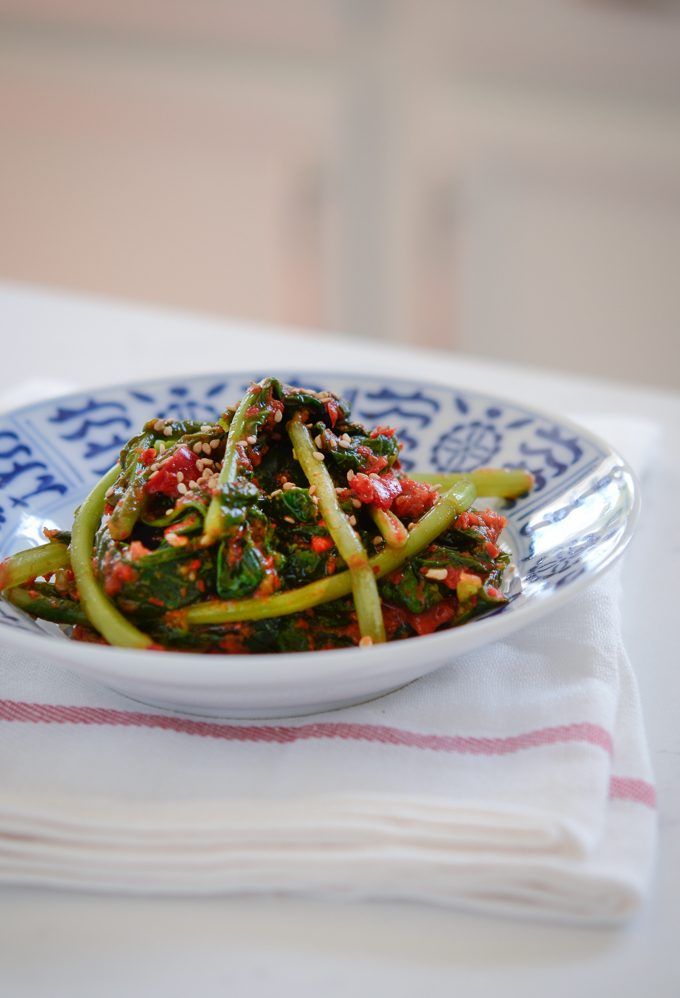 Turnip kimchi is served in a blue and white bowl over a white kitchen towel.