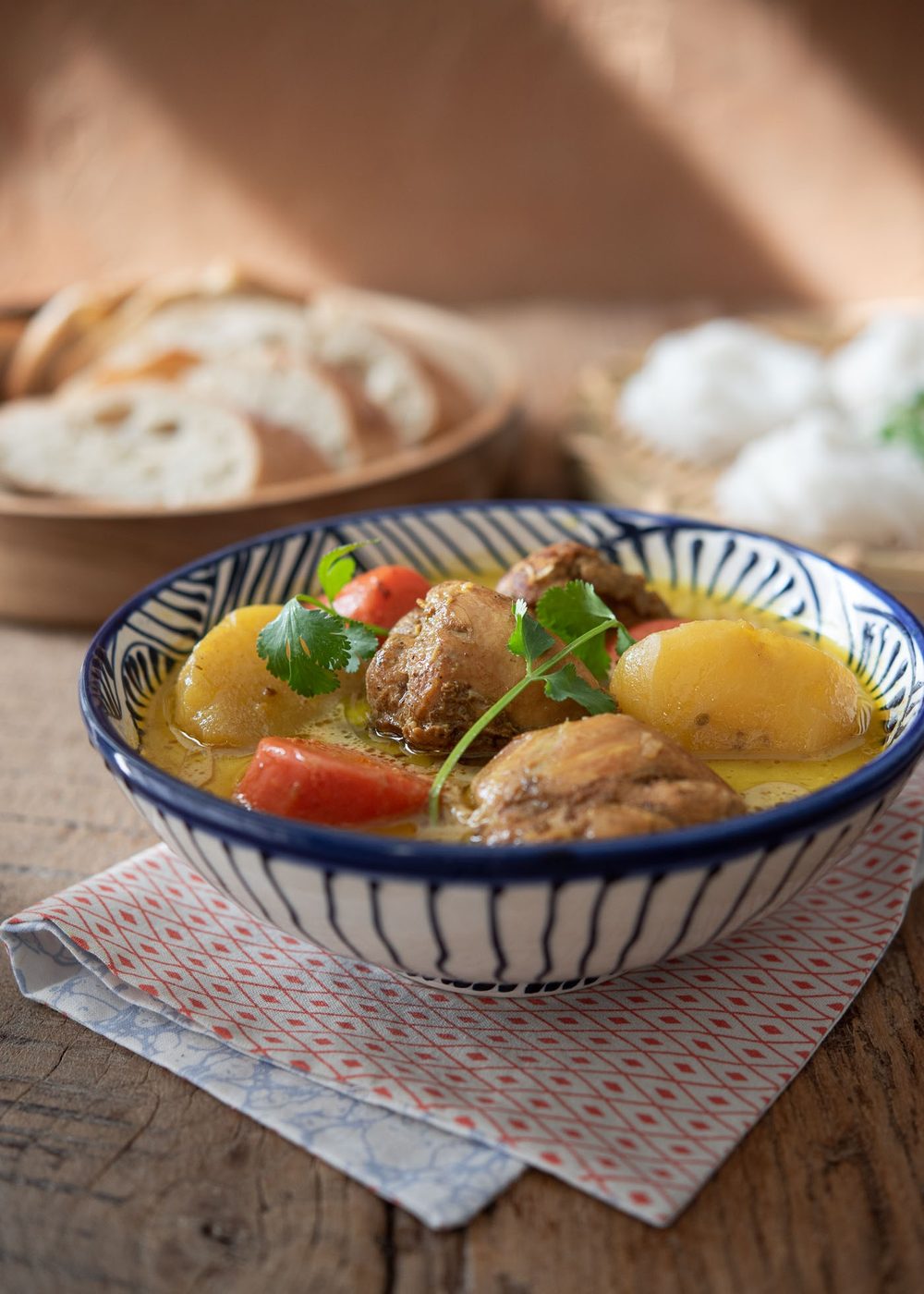 Fragrant cà ri gà garnished with herbs, alongside rice noodles and baguette