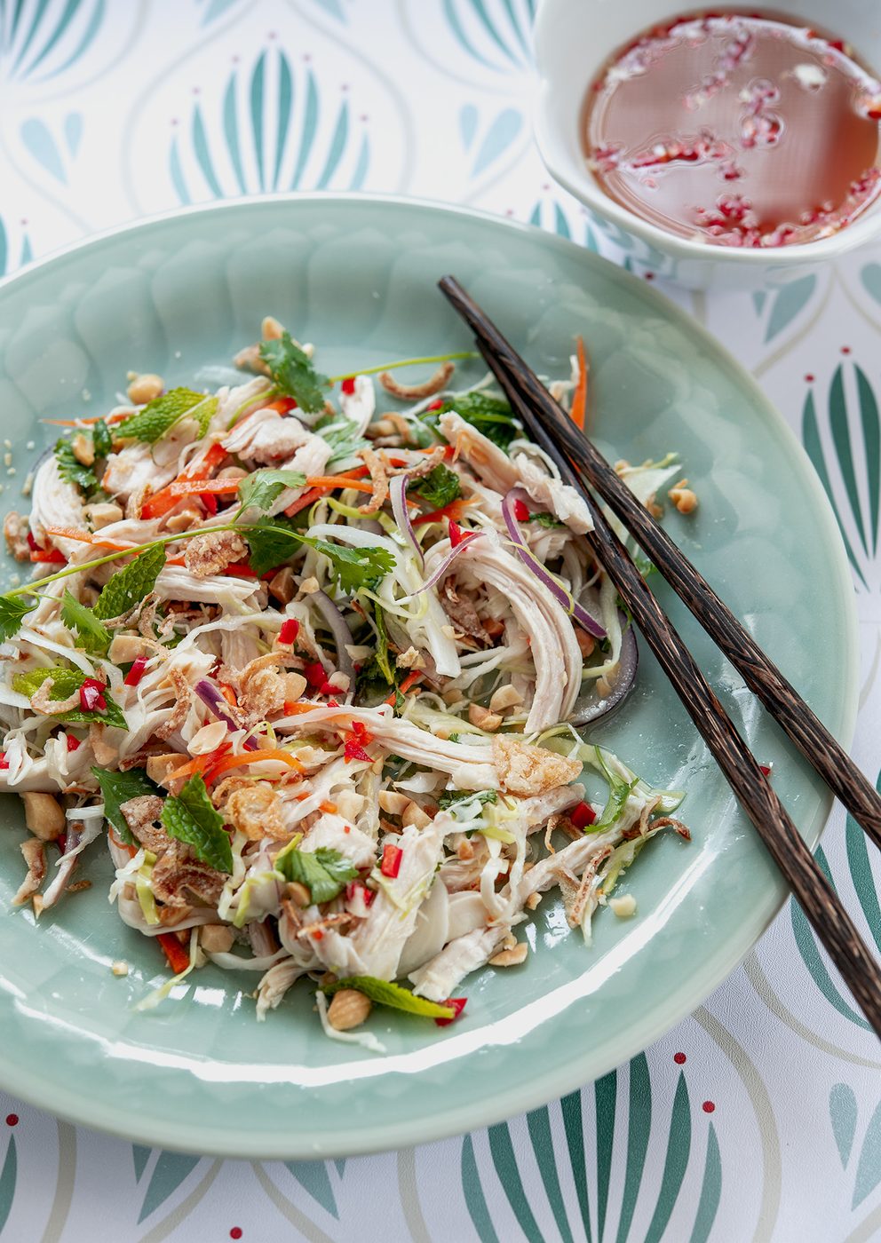 Tasty Vietnamese chicken salad is served on a green plate with fish sauce dressing.