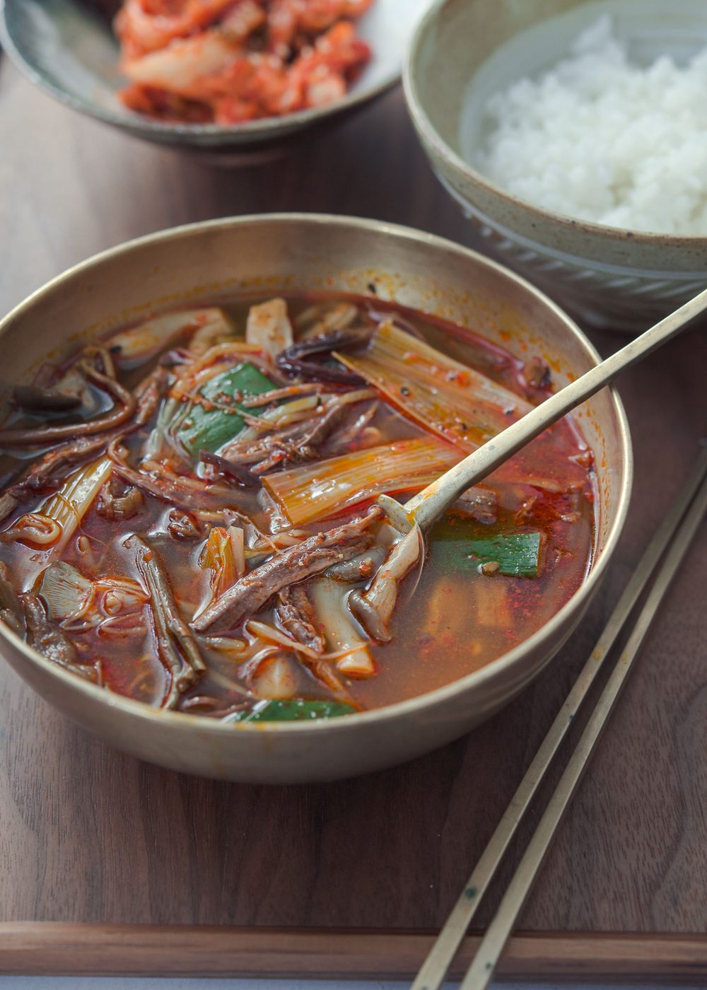 A serving bowl of yukgaejang with a spoon ready to eat