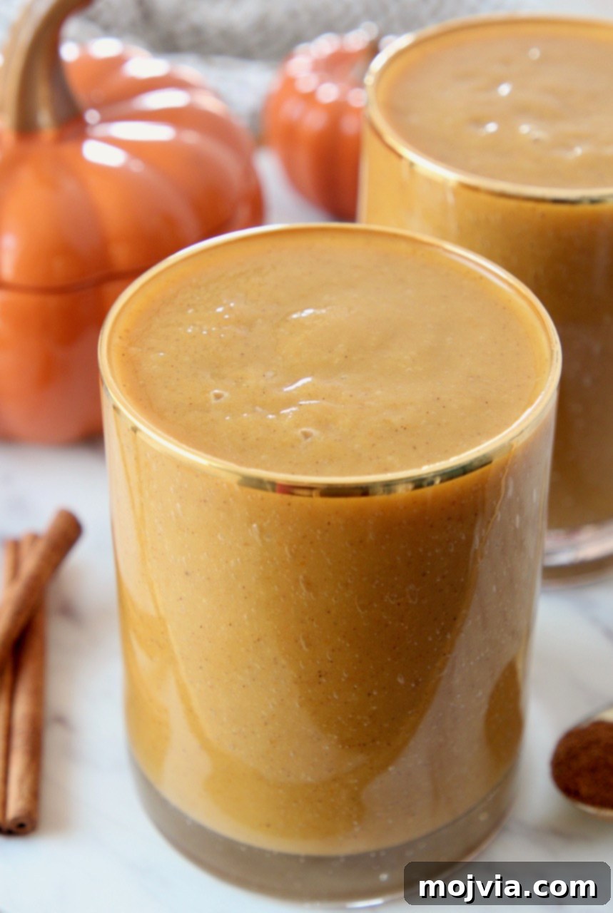 Autumn Glow Smoothie 4 A freshly blended vegan pumpkin smoothie in a stylish glass with a gold rim, ready to be served.