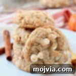 Pumpkin spice white chocolate chip cookies stacked up on a plate
