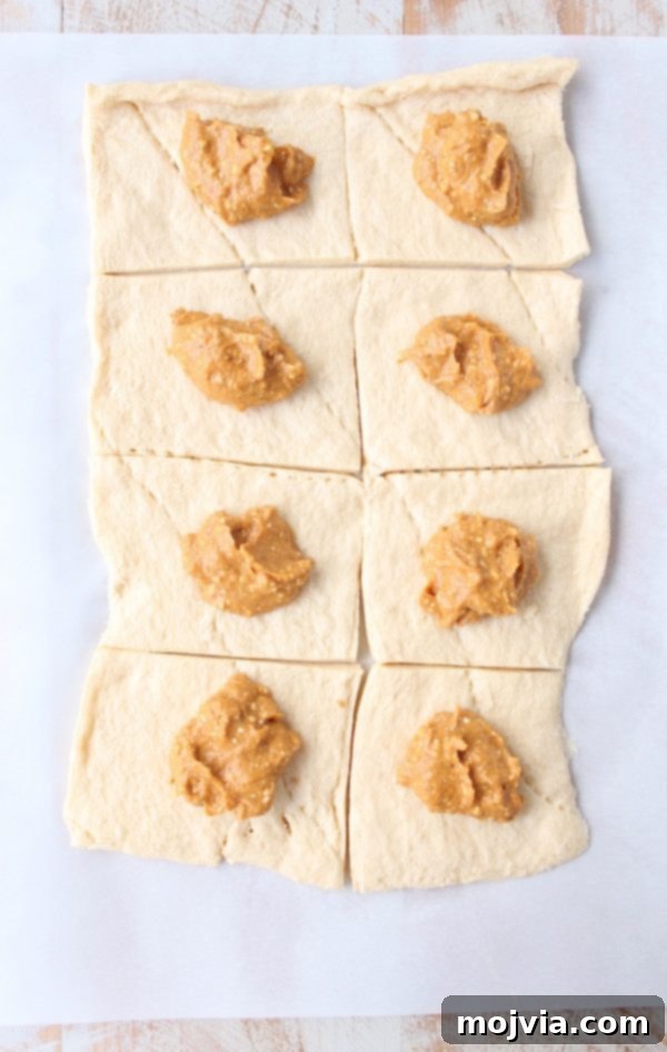 Spiced Pumpkin Pockets 4 Pumpkin cream cheese filling carefully dolloped onto individual squares of crescent roll dough, prepared for folding.