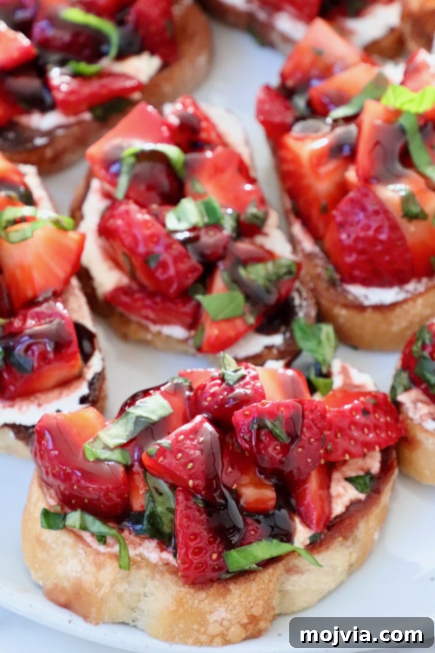Strawberry Bliss Bites 2 Fresh Strawberry Bruschetta on toasted baguette slices arranged beautifully on a rustic white plate, garnished with basil leaves, perfect for a summer appetizer.