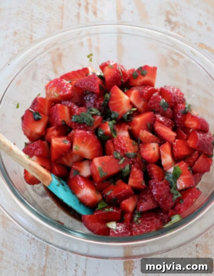 Strawberry Bliss Bites 5 Finely diced fresh strawberries, vibrant green basil, and a generous splash of balsamic vinegar combined in a mixing bowl, creating the delicious bruschetta topping.