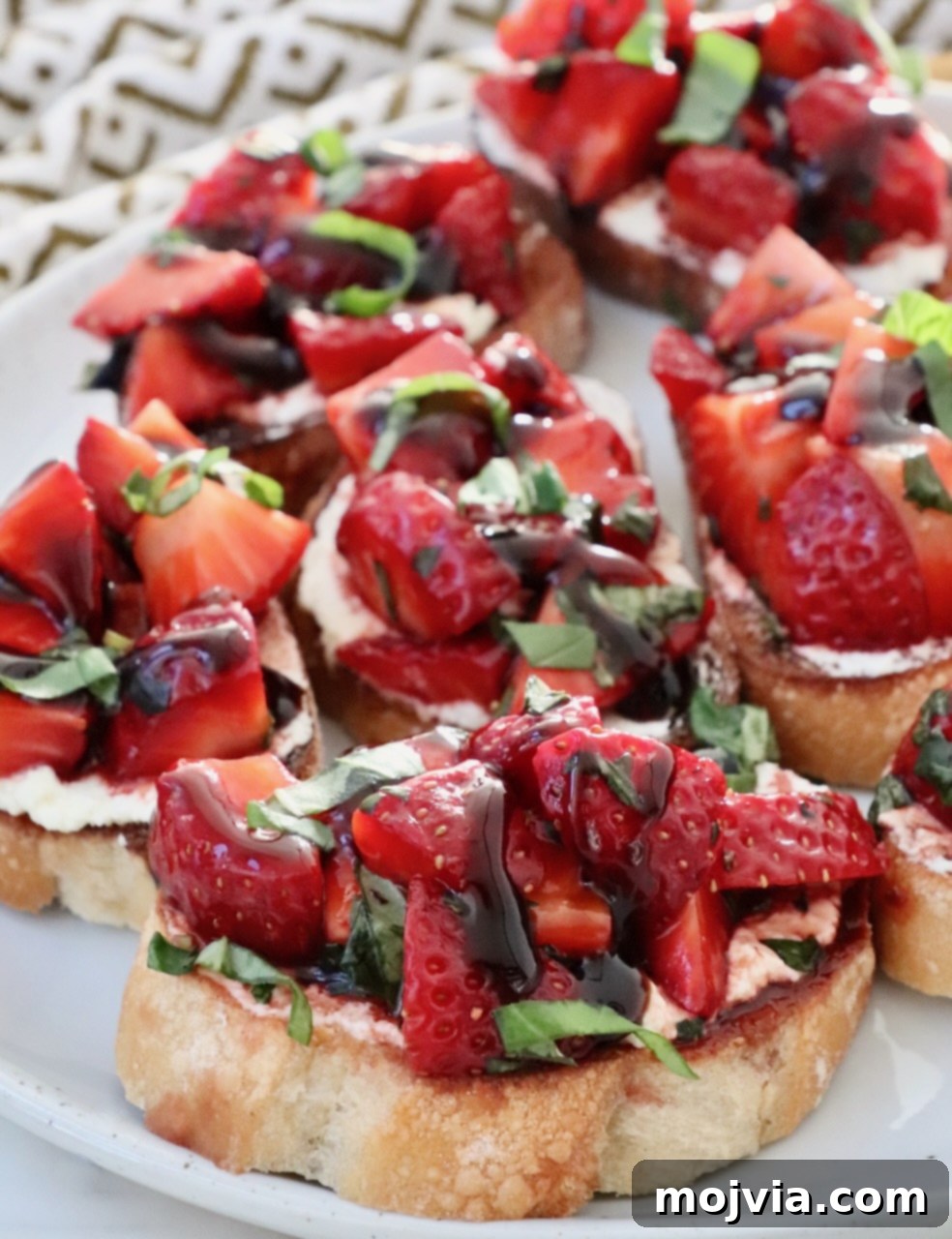 Strawberry Bliss Bites 8 A stunning close-up of a single piece of Strawberry Bruschetta, expertly crafted and placed on a white plate, highlighting the vibrant colors and appealing textures of the strawberries, goat cheese, and toasted baguette.