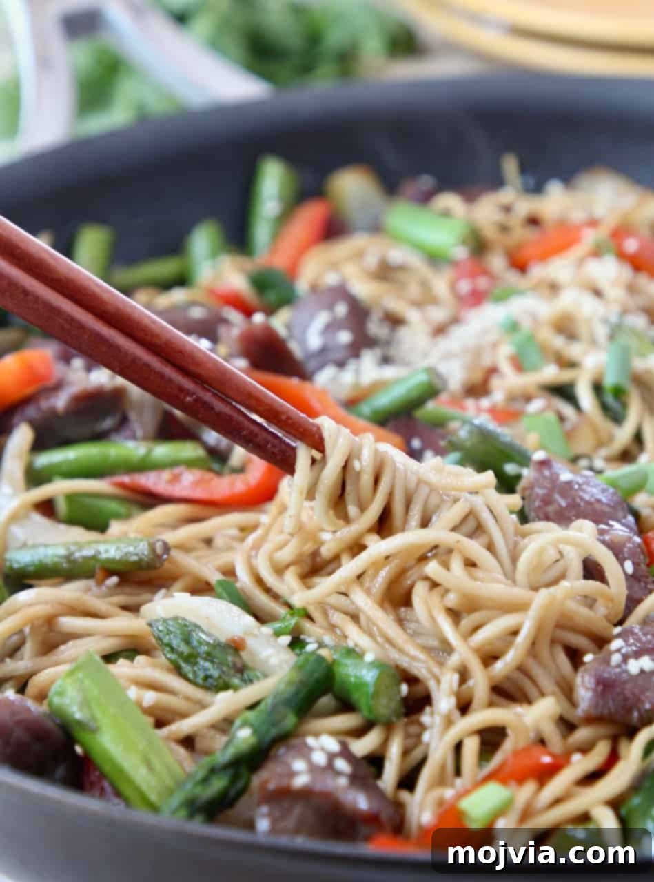 Perfect Beef Stir Fry 5 chopsticks swirling noodles in skillet of stir fry