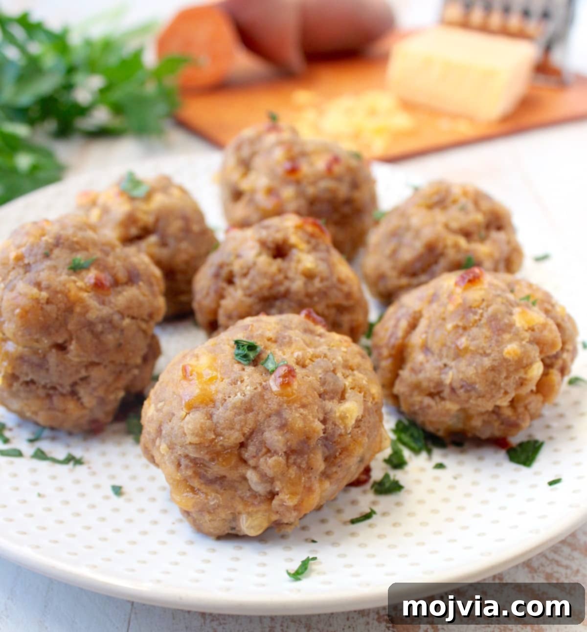 An artistic arrangement of golden sweet potato sausage balls on a white plate, garnished for presentation.
