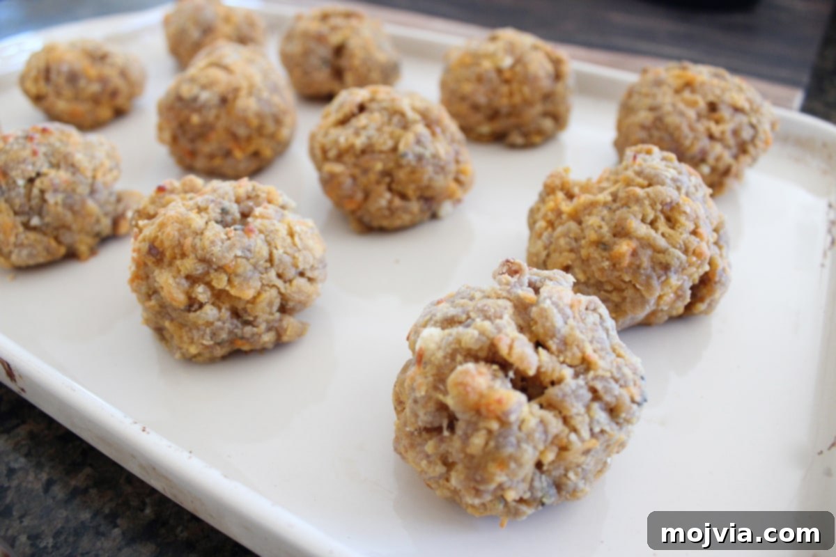 A baking sheet filled with freshly baked, golden-brown gluten-free sweet potato sausage balls, hot out of the oven.