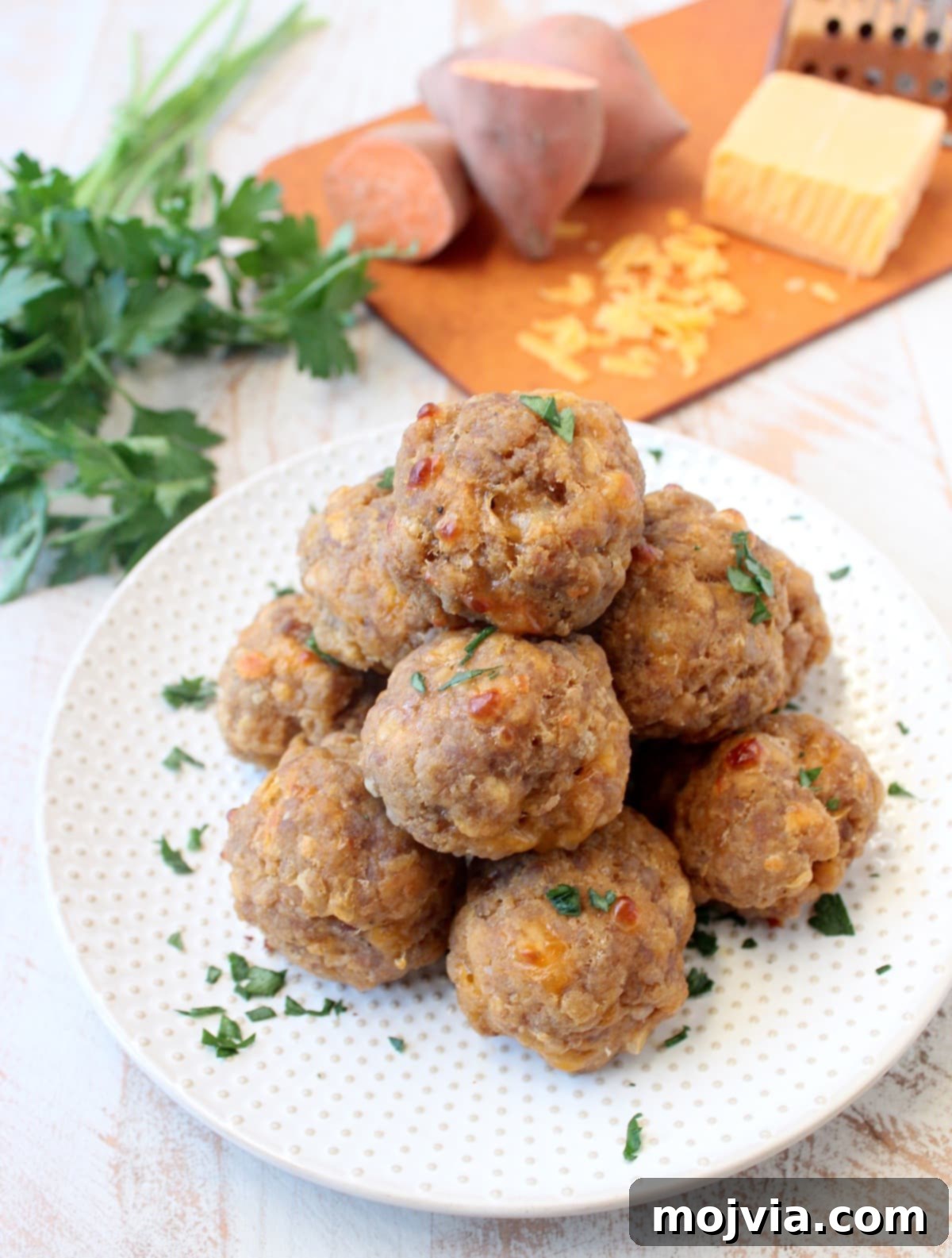 A close-up of perfectly cooked sweet potato sausage balls artfully arranged on a simple white plate, ready to be enjoyed.