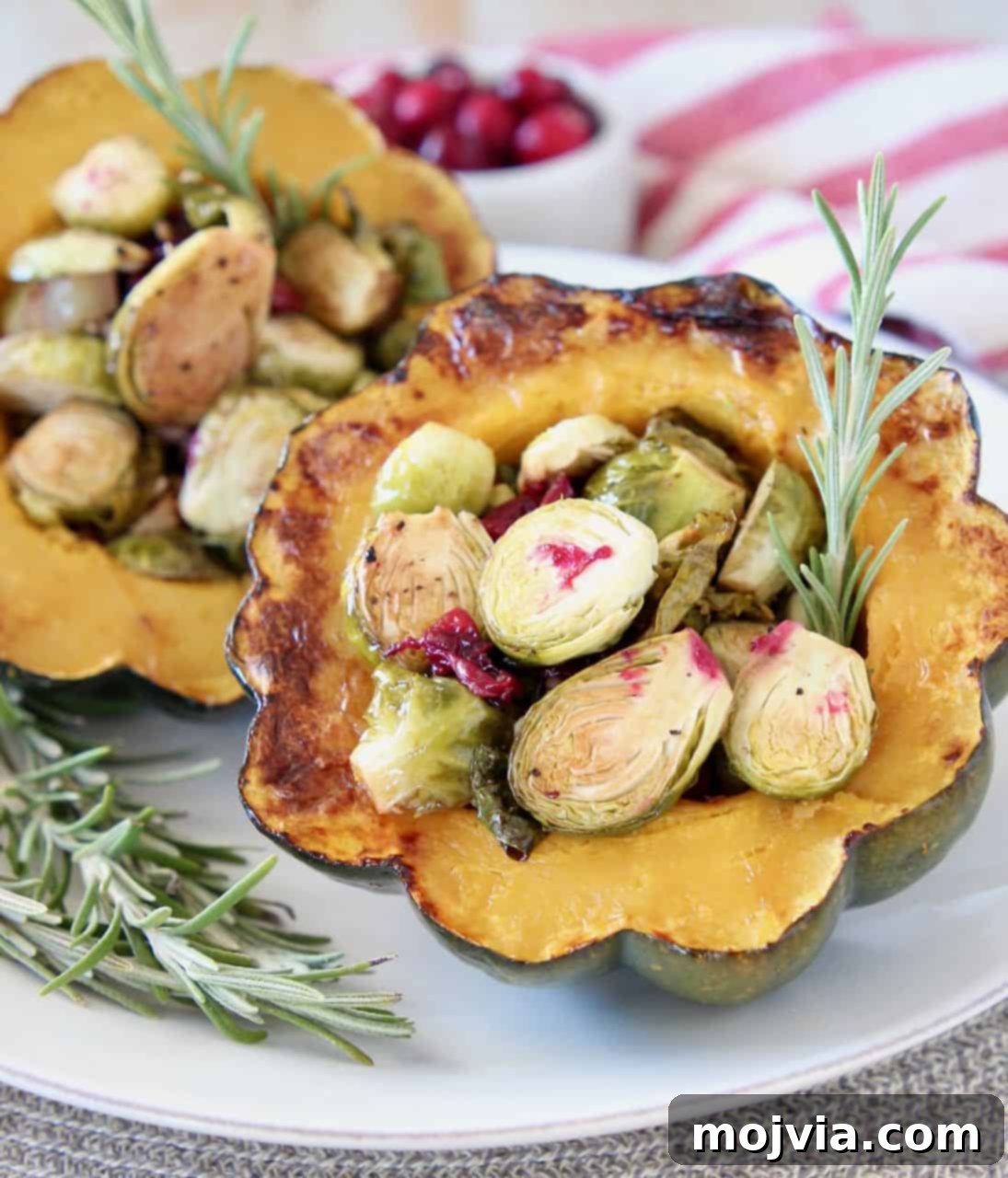 Autumn Harvest Acorn Squash with Cranberry and Brussels Sprout Filling 5 Stuffed acorn squash halves on plate filled with roasted brussels sprouts and cranberries, ready to be served