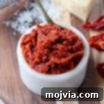 Sun dried tomato pesto in small white bowl on wood cutting board