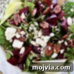 Beet salad in a bowl topped with pecans and feta cheese crumbles, ready to be served