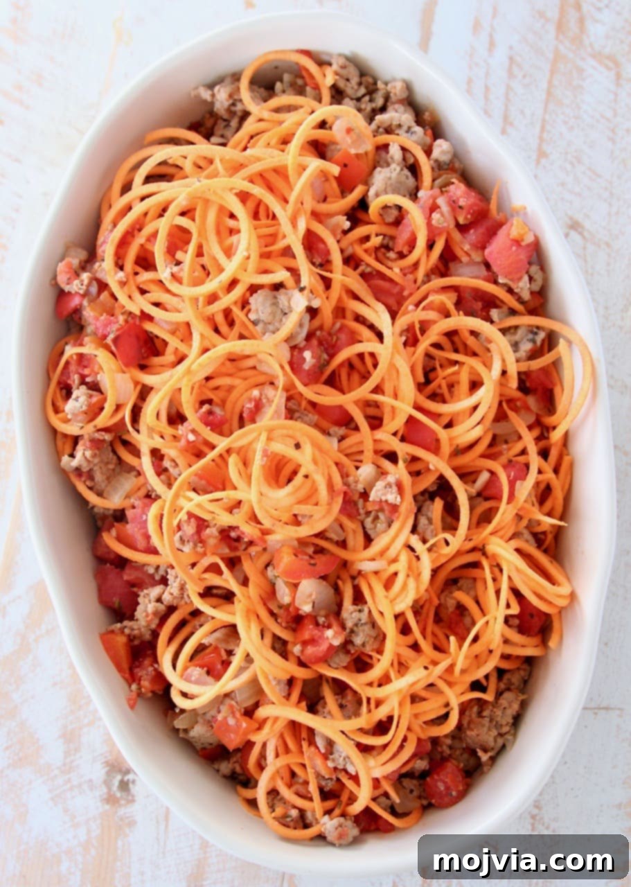 Tuscan Turkey Sweet Potato Bake 4 Sweet potato noodles, savory ground turkey, and diced tomatoes beautifully combined in an oval baking dish before baking, ready for the cheese topping.