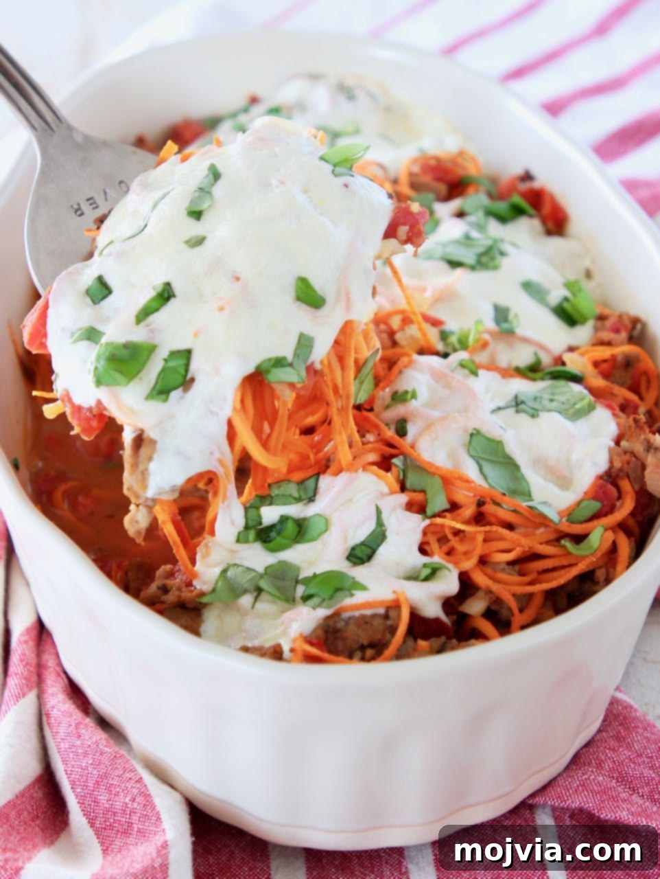 Tuscan Turkey Sweet Potato Bake 5 Large serving fork scooping out a generous portion of creamy Italian turkey sweet potato casserole, revealing the delicious layers of melted mozzarella and perfectly cooked ingredients.