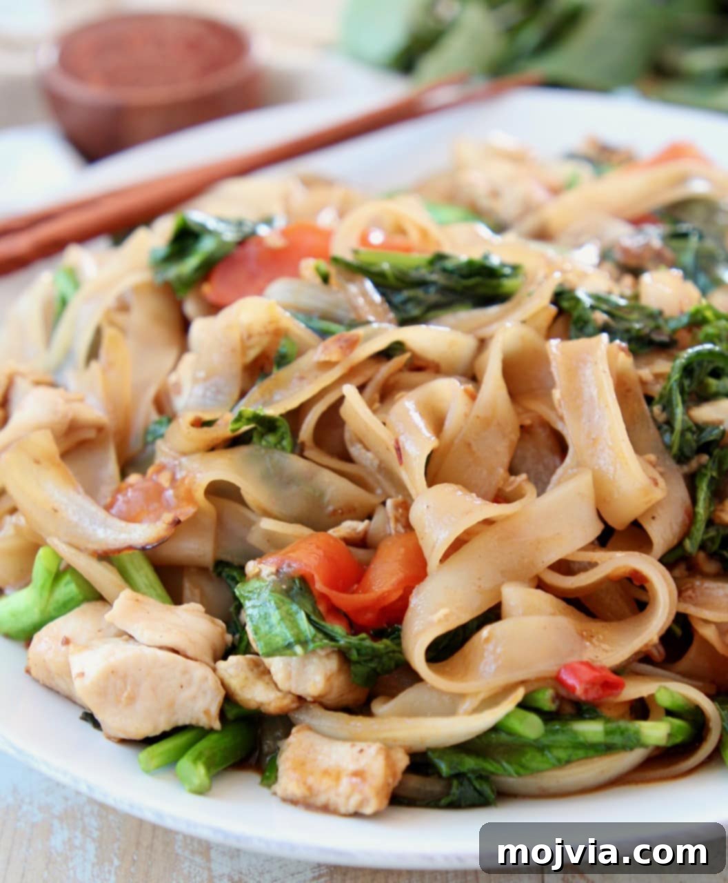 Thai wide noodles stir fried with Chinese broccoli on white plate