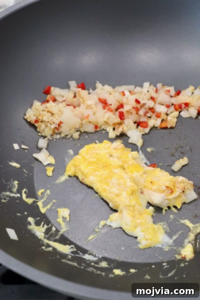 scrambled eggs with cooked diced vegetables in large wok