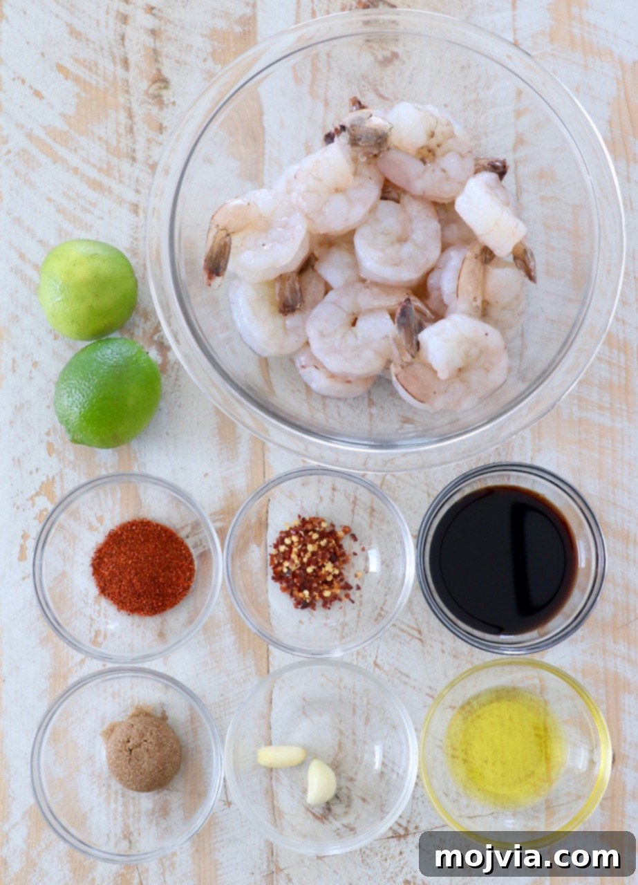 A vibrant selection of ingredients laid out, including fresh shrimp, limes, garlic, soy sauce, brown sugar, chili powder, red pepper flakes, and olive oil, all ready for the chili lime garlic marinade.