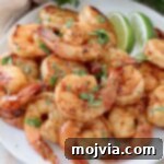 cooked shrimp piled up on plate with lime wedges