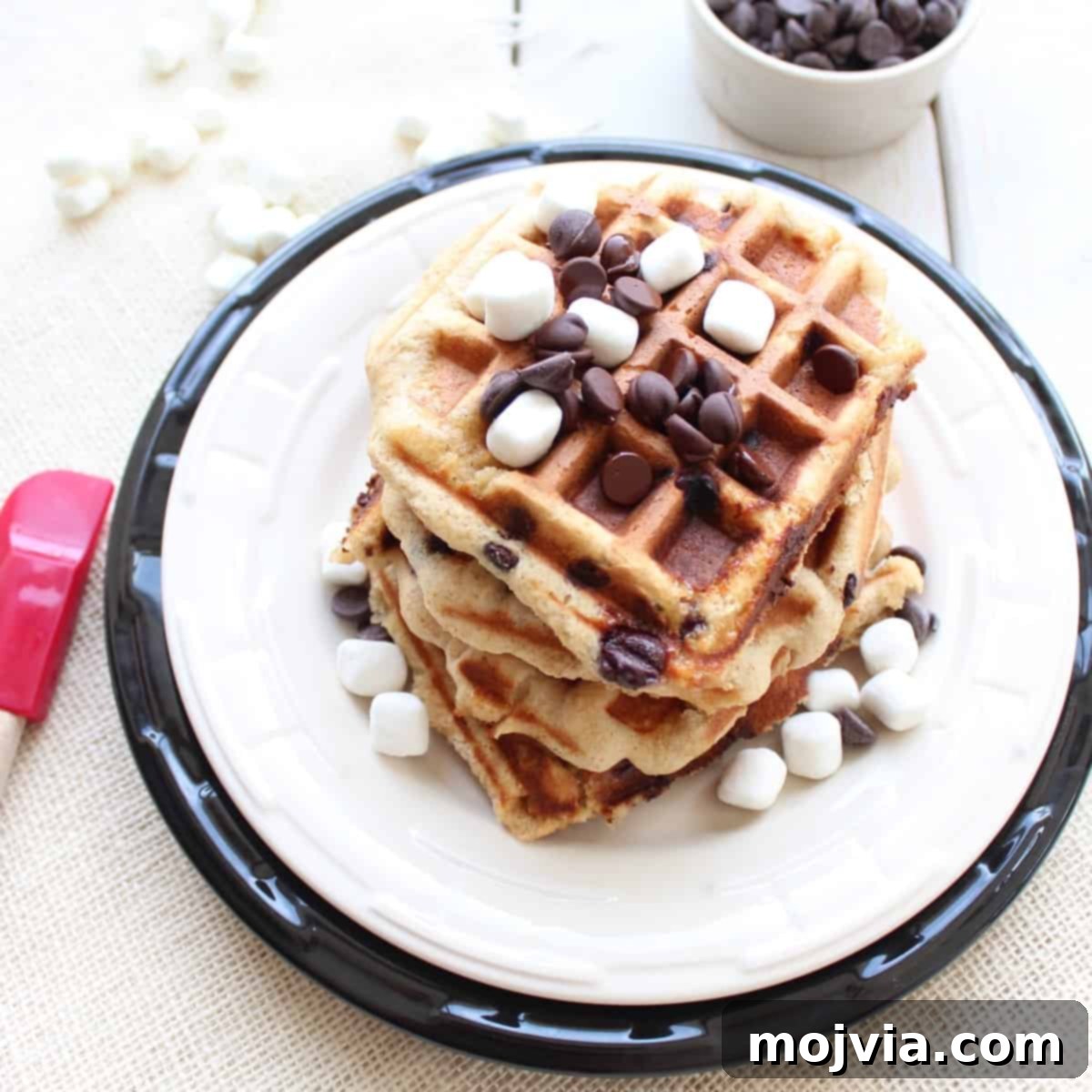 Stacked S'mores Waffles on a plate with chocolate chips and mini marshmallows