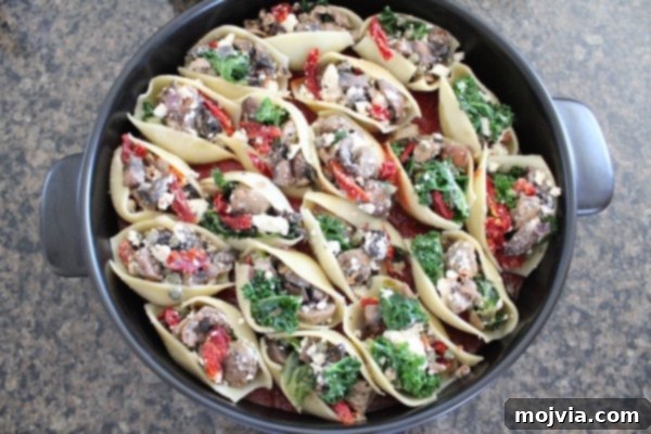 Sun-Drenched Sausage & Cheese Pasta Shells 10 Neatly arranged Mediterranean Stuffed Shells resting in a pot, ready to be topped with more sauce and baked to perfection.
