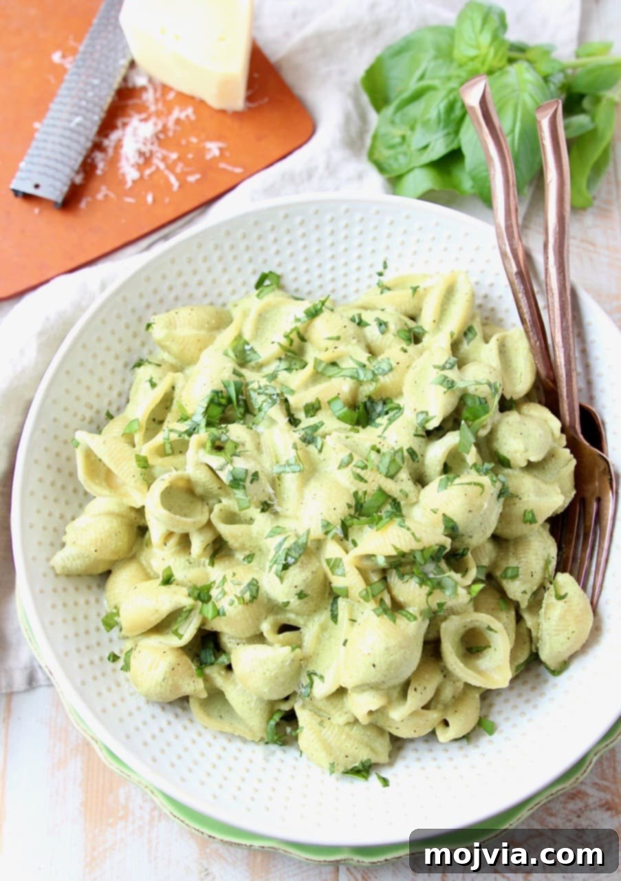 Vibrant Basil Pesto Pasta with Gooey Cheese 2 Cheesy pesto pasta shells in large white bowl with copper forks in the bowl