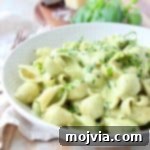 Creamy pesto pasta in white bowl with fresh basil on top