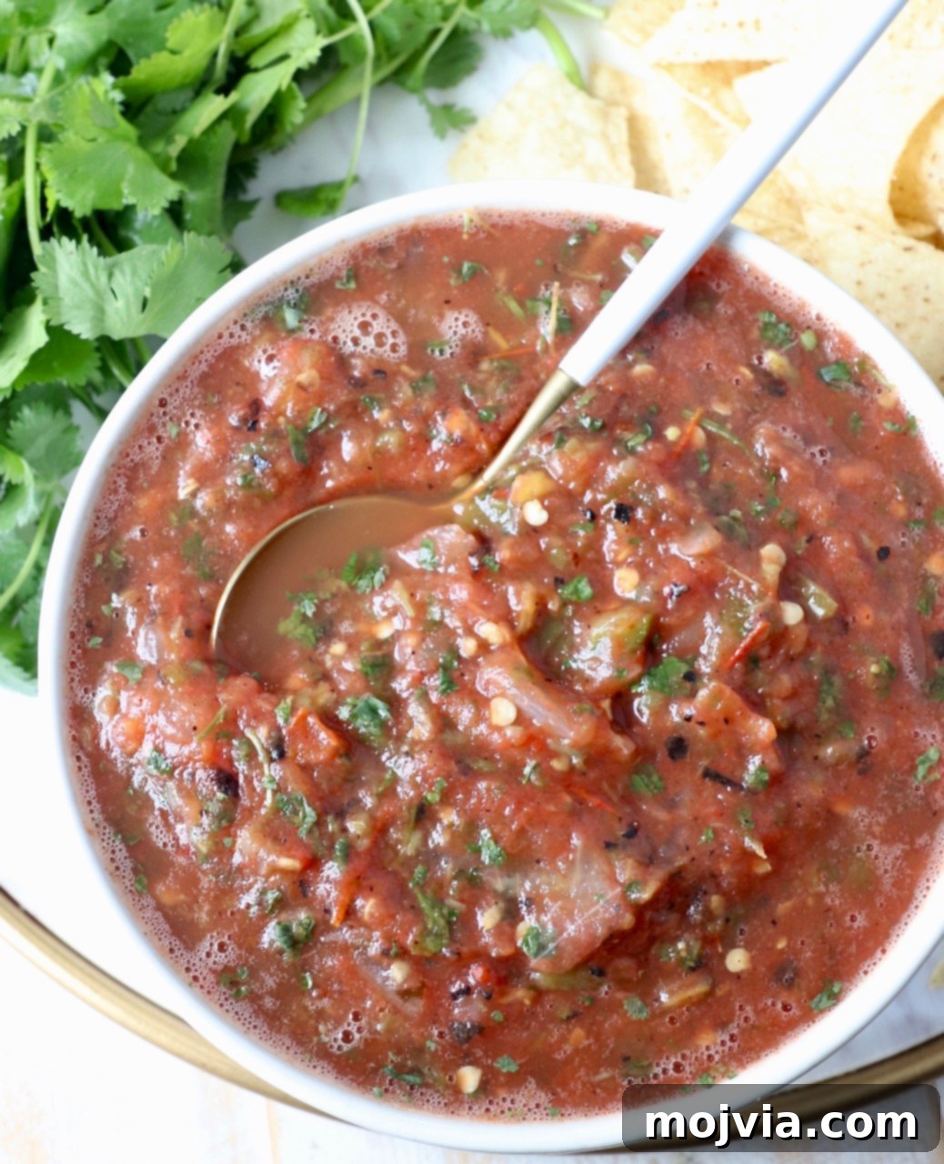 Your Go-To 10-Minute Fresh Salsa 7 A serving bowl of easy restaurant-style tomato salsa with a spoon, highlighting its inviting, rustic texture.
