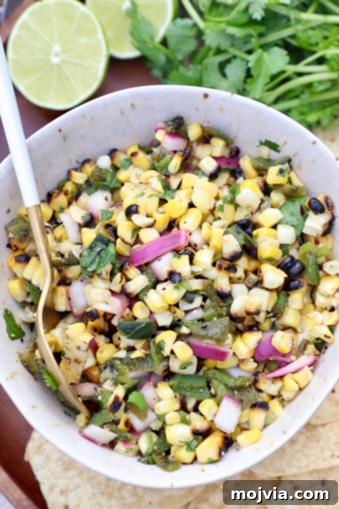 Fiesta Corn Salsa 2 A bowl of freshly made roasted corn salsa with a spoon, ready to be served.