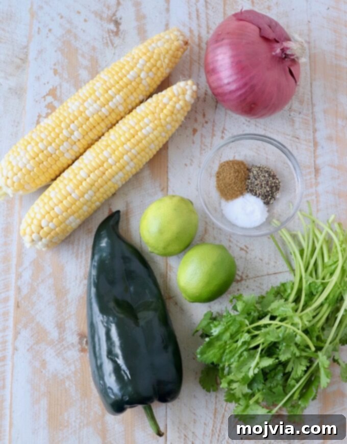 Fiesta Corn Salsa 3 A vibrant selection of fresh ingredients including corn on the cob, a poblano pepper, red onion, and cilantro, laid out for making corn salsa.
