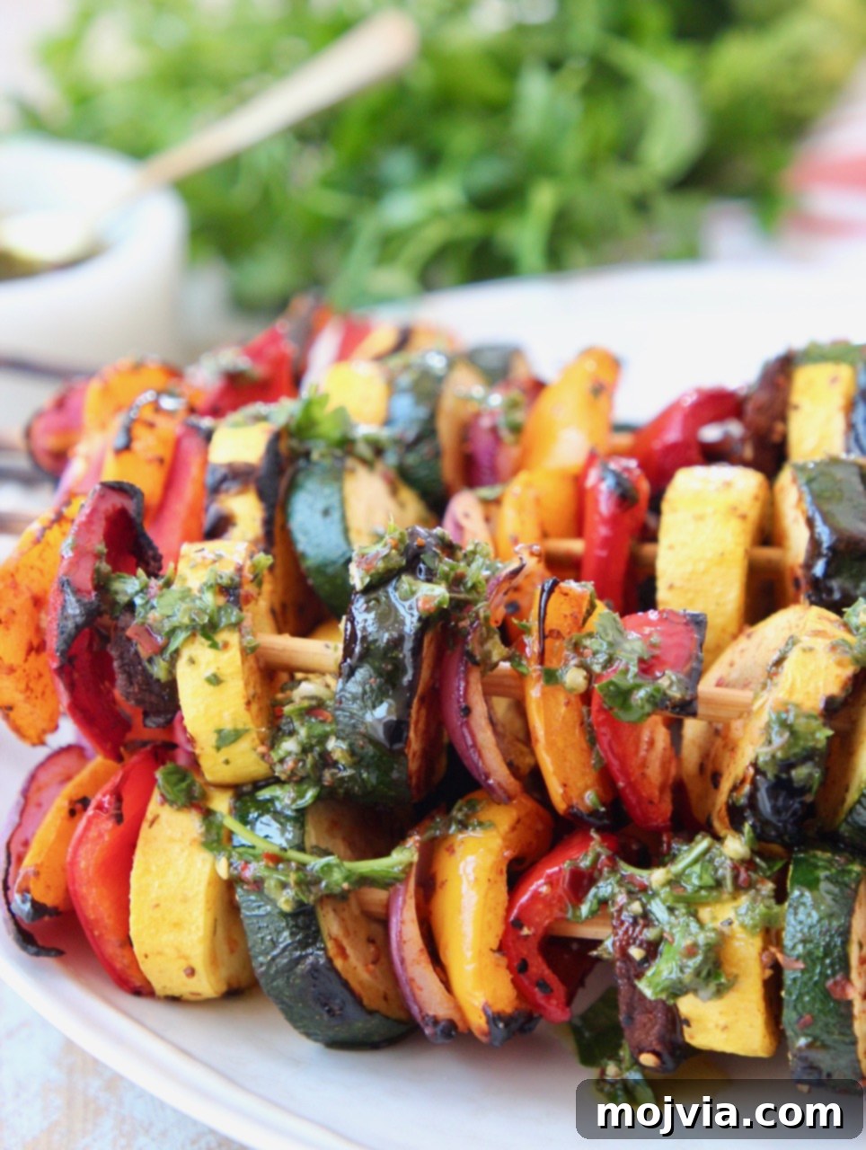 Vibrant Grilled Vegetable Skewers 5 Grilled vegetable skewers arranged on a plate with fresh chimichurri sauce drizzled generously over them, enhancing their flavor and presentation.