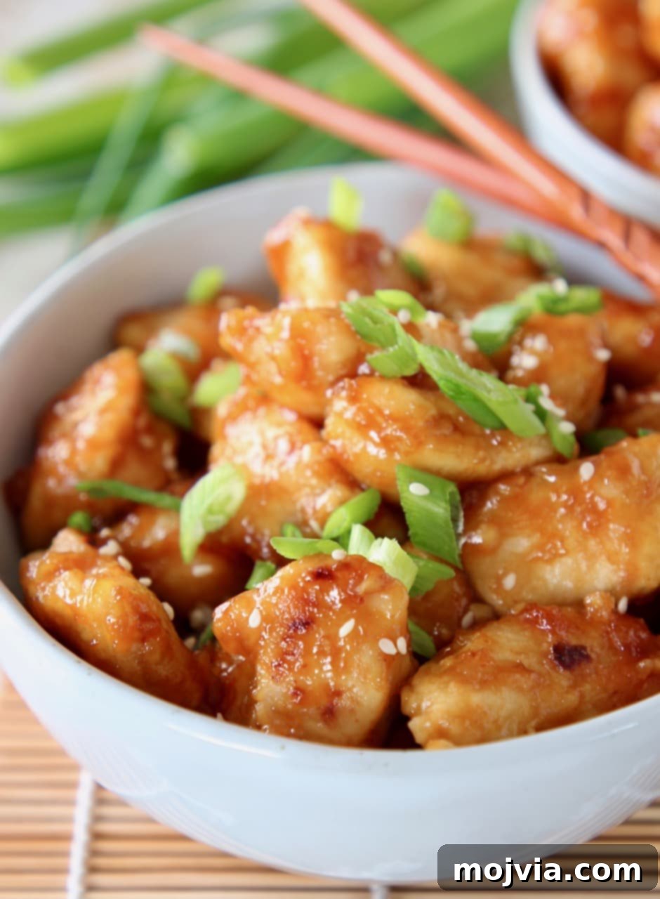 Zesty Gluten-Free Orange Chicken 2 Gluten-Free Orange Chicken in a bowl with diced scallions and chopsticks