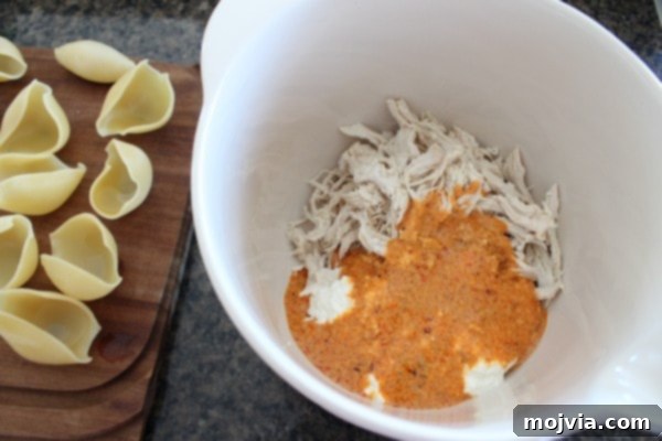Mixing shredded chicken and ricotta cheese with buffalo Alfredo sauce for the filling.