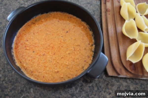 Spreading buffalo Alfredo sauce in the bottom of a baking dish.