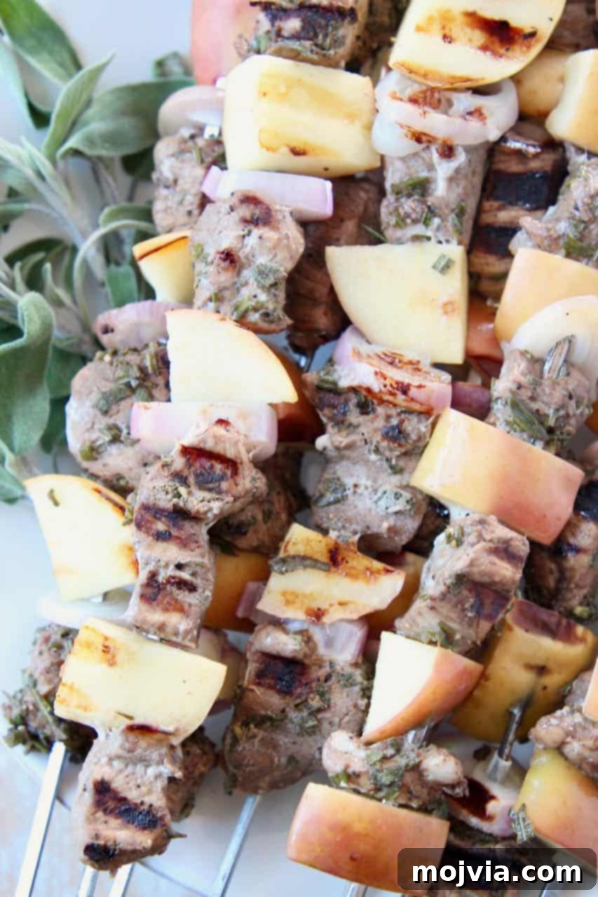 Fragrant Rosemary Sage Pork Skewers 3 Close-up of marinated pork tenderloin skewers with apples and shallots on a plate