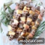 Pork and apple skewers on plate with fresh herbs