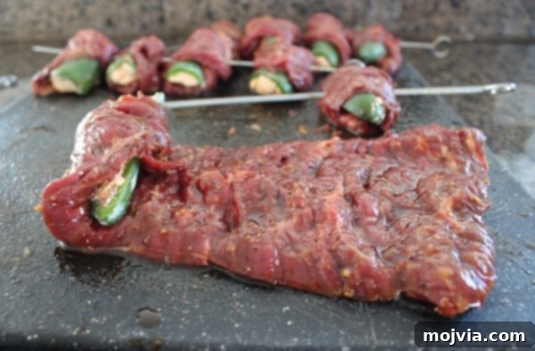 Smoky Sriracha Steak Popper Skewers 12 Steak strips being wrapped around stuffed jalapeño halves