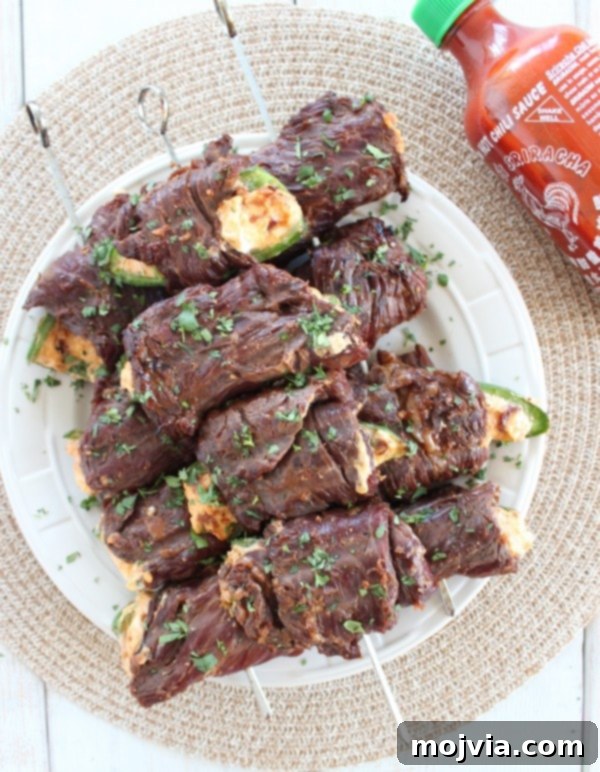 Smoky Sriracha Steak Popper Skewers 16 Several grilled Sriracha Steak Wrapped Jalapeño Skewers on a white plate