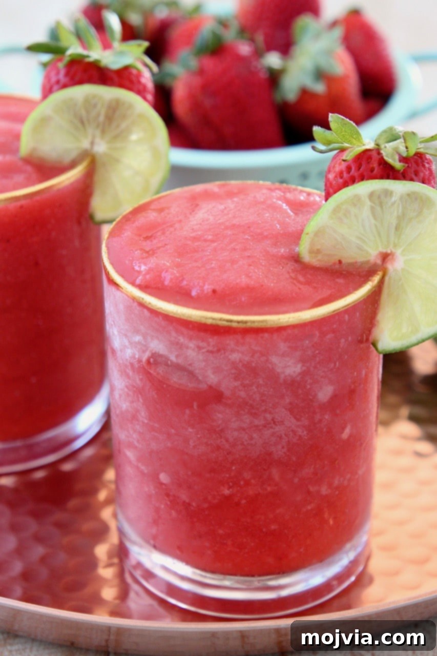 Basil Infused Strawberry Daiquiri 4 A freshly blended frozen strawberry daiquiri in a clear glass, garnished with a vibrant green lime wedge, ready to be enjoyed as a refreshing summer drink.