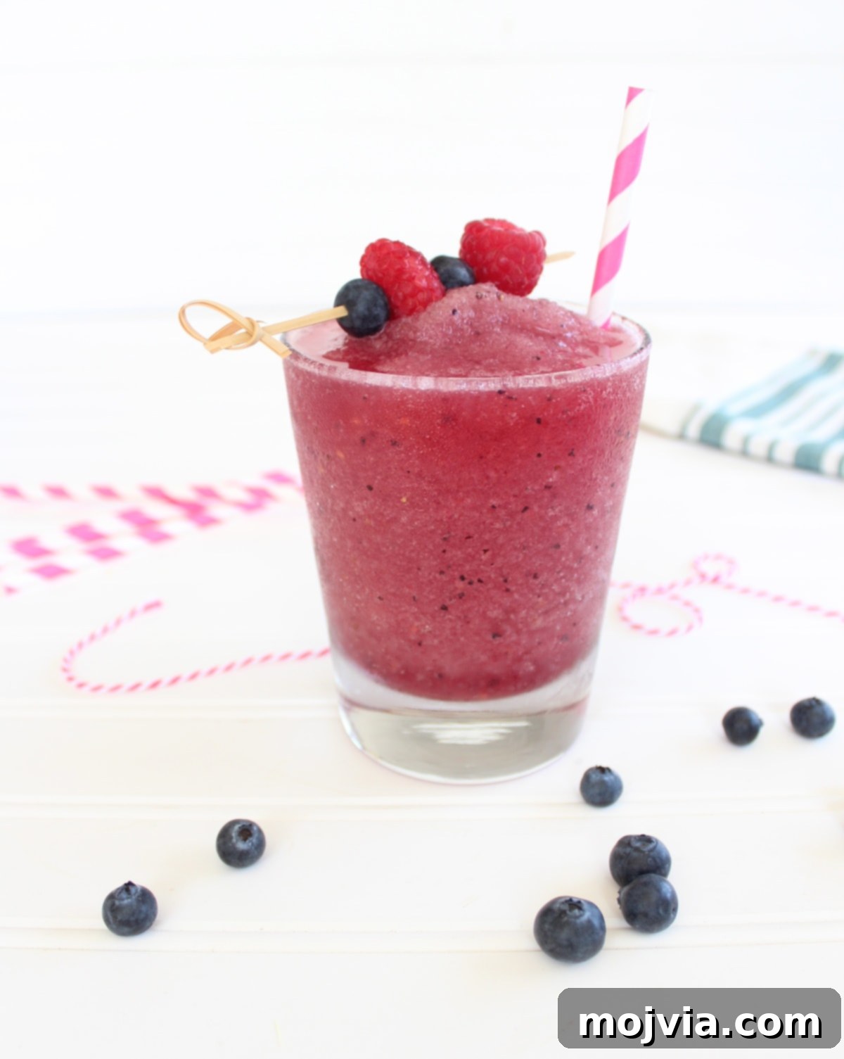 Vibrant Frozen Berry Sangria in a glass, garnished with a skewer of fresh strawberries, blueberries, and raspberries