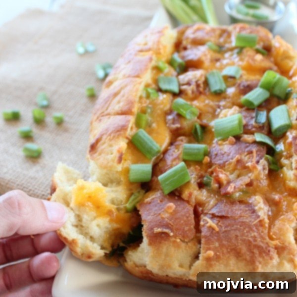 Hands pulling apart a piece of the Loaded Baked Potato Bread