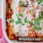 Italian enchiladas in white baking dish topped with fresh basil